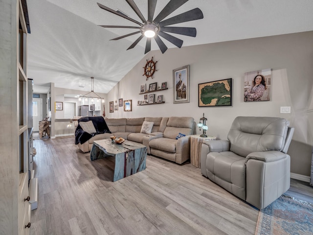 living room featuring light wood-type flooring, ceiling fan with notable chandelier, and lofted ceiling