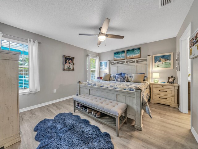 bedroom featuring ceiling fan, a textured ceiling, and light hardwood / wood-style flooring