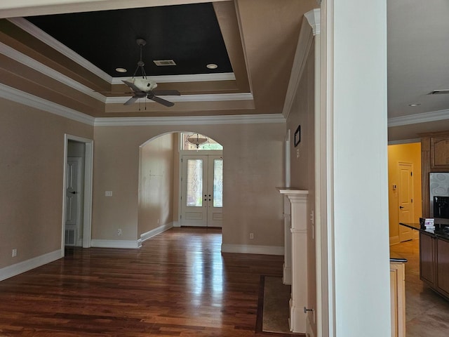 spare room with ornamental molding, a tray ceiling, ceiling fan, and dark wood-type flooring