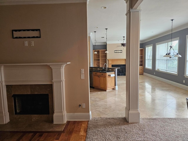 unfurnished living room featuring light wood-type flooring, sink, ceiling fan with notable chandelier, decorative columns, and ornamental molding