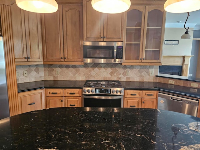 kitchen with pendant lighting, backsplash, appliances with stainless steel finishes, dark stone countertops, and crown molding