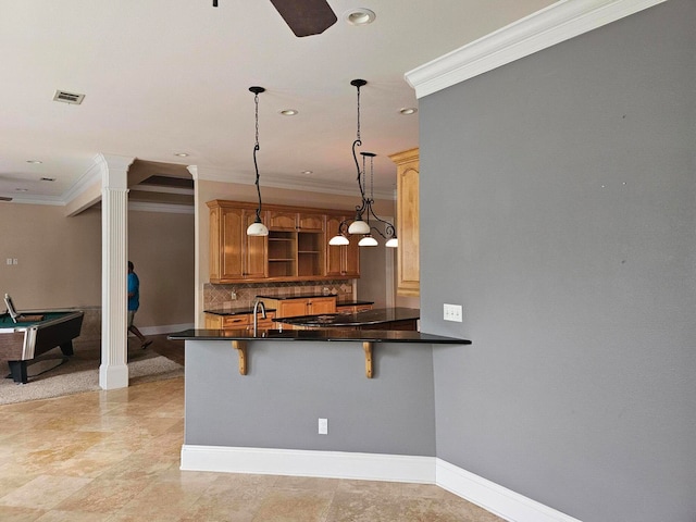 kitchen with ornate columns, decorative light fixtures, a kitchen breakfast bar, and kitchen peninsula