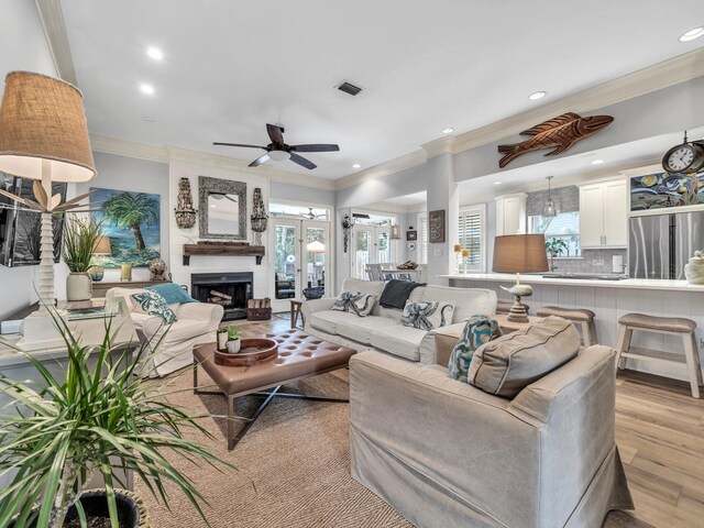 living room with ceiling fan, ornamental molding, and light wood-type flooring