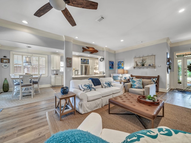 living room with light wood-type flooring, a wealth of natural light, crown molding, and recessed lighting