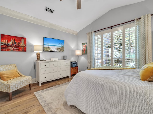 bedroom with ceiling fan, light wood-style flooring, visible vents, vaulted ceiling, and ornamental molding