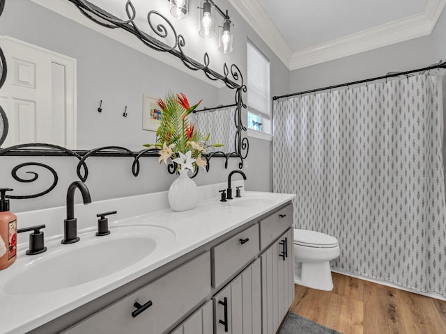 bathroom with crown molding, a sink, and wood finished floors