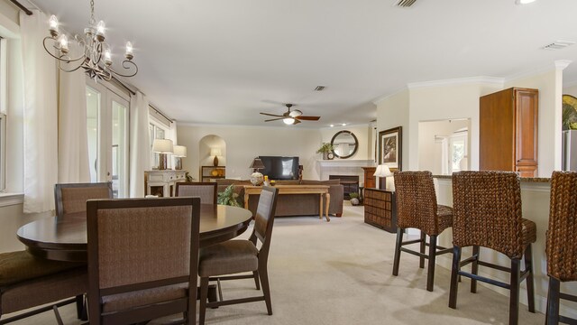 dining room featuring light colored carpet, ceiling fan with notable chandelier, and crown molding