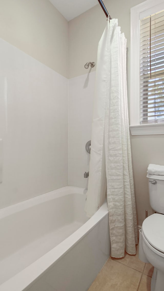 bathroom with tile patterned flooring, shower / bath combo with shower curtain, and toilet