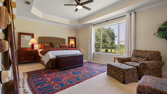 bedroom with ceiling fan, crown molding, a tray ceiling, and light colored carpet