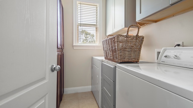 laundry area featuring light tile patterned flooring, washer and dryer, cabinets, and a healthy amount of sunlight