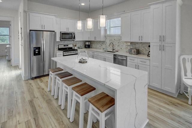 kitchen featuring light wood-type flooring, a wealth of natural light, a center island, and stainless steel appliances