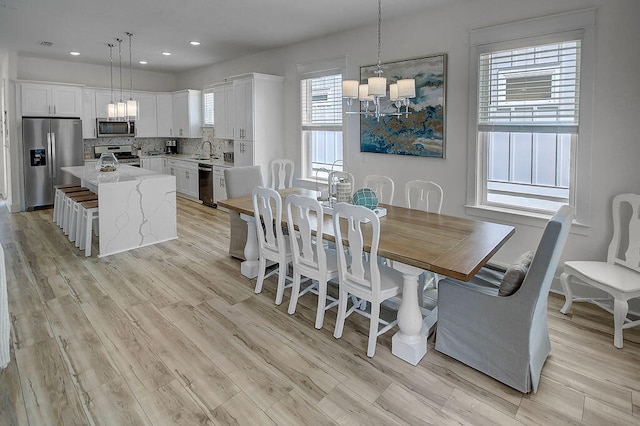 dining space with light hardwood / wood-style flooring, sink, and plenty of natural light