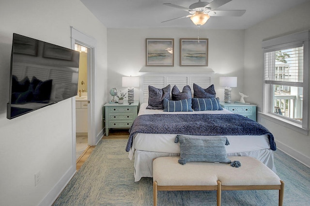 bedroom featuring ceiling fan, ensuite bath, and light hardwood / wood-style flooring