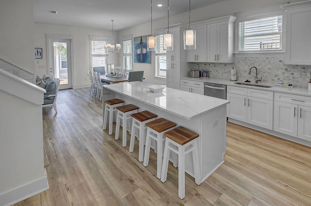 kitchen featuring light hardwood / wood-style flooring, tasteful backsplash, dishwasher, sink, and a center island