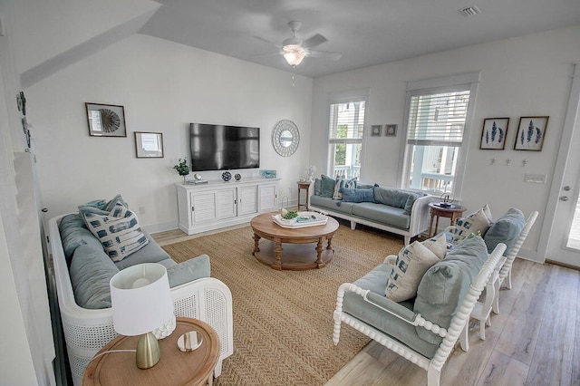 living room featuring ceiling fan, light hardwood / wood-style floors, and lofted ceiling