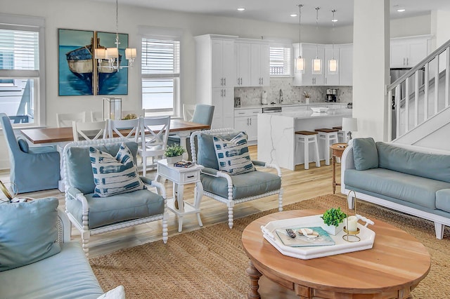 living room featuring light wood-type flooring, sink, and a notable chandelier