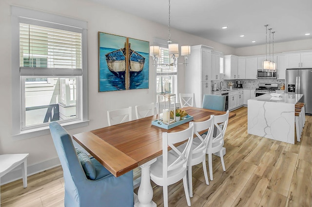 dining area with a wealth of natural light, sink, and light hardwood / wood-style flooring