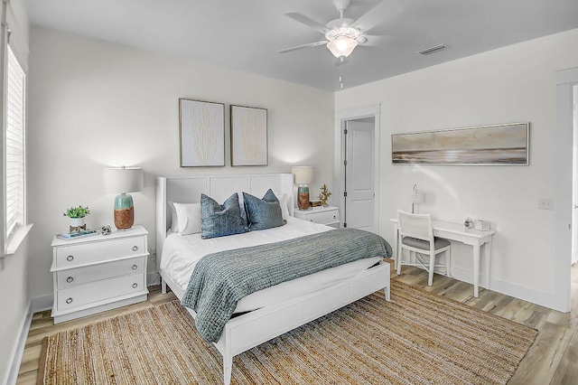 bedroom featuring ceiling fan, light hardwood / wood-style floors, and multiple windows