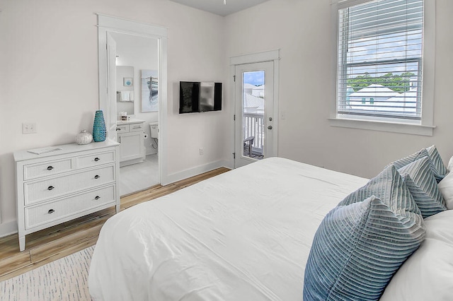 bedroom with light wood-type flooring, access to outside, and ensuite bathroom