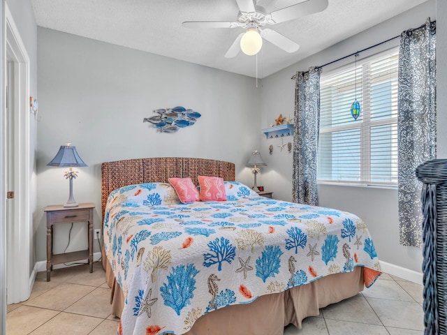 bedroom featuring light tile patterned floors, ceiling fan, baseboards, and a textured ceiling