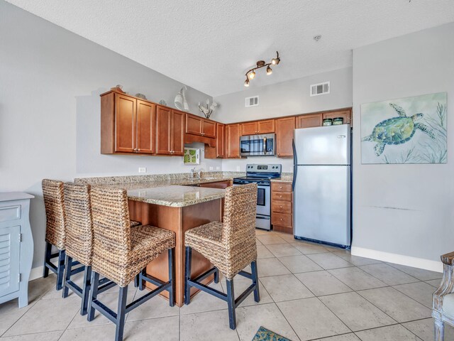 kitchen with appliances with stainless steel finishes, sink, a textured ceiling, track lighting, and kitchen peninsula