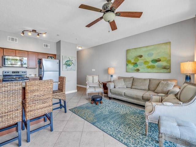 living area with visible vents, ceiling fan, a textured ceiling, and light tile patterned floors