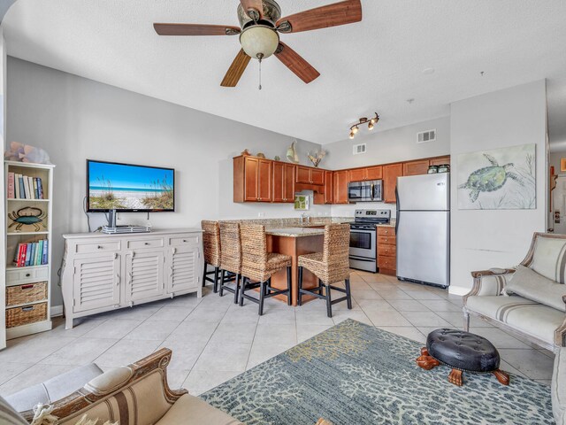 tiled living room featuring ceiling fan, track lighting, a textured ceiling, and sink