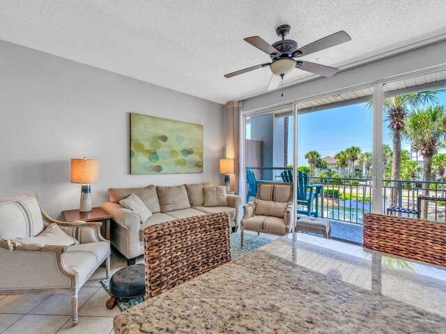 living room featuring ceiling fan, a textured ceiling, and light tile patterned flooring