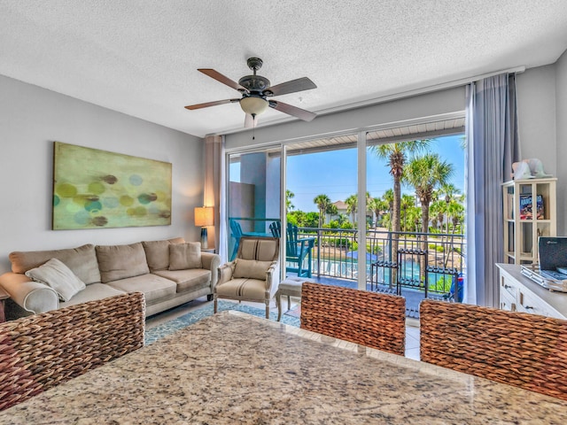 living area with ceiling fan and a textured ceiling