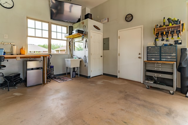 garage with sink, stainless steel fridge, and electric panel