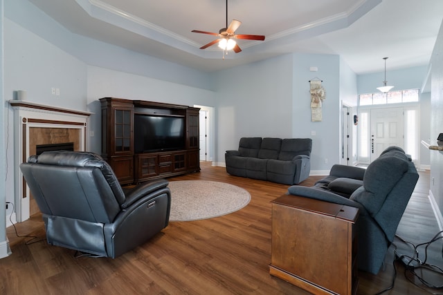 living room with ceiling fan, a raised ceiling, and dark hardwood / wood-style floors