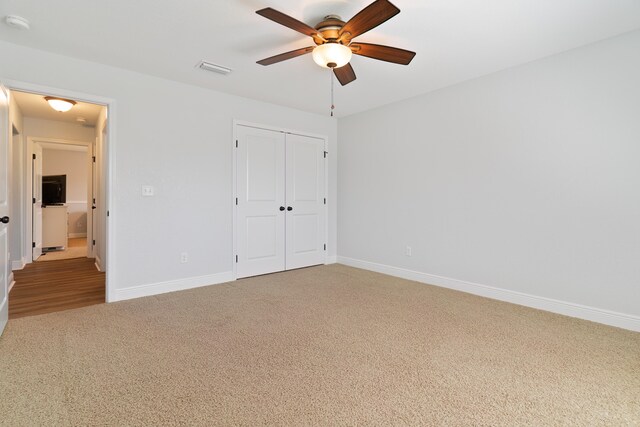 unfurnished bedroom with light colored carpet, a closet, and ceiling fan