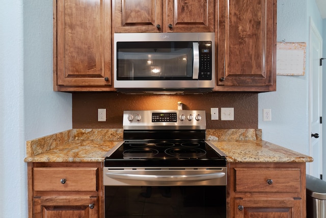 kitchen with appliances with stainless steel finishes and light stone counters