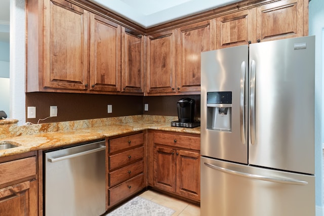 kitchen featuring stainless steel appliances, light tile patterned flooring, and light stone counters