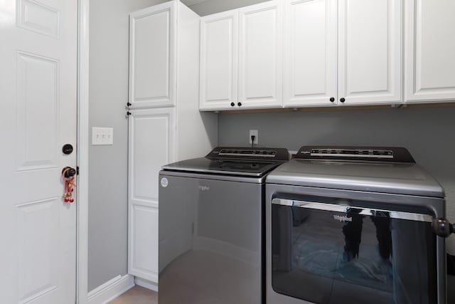 clothes washing area featuring cabinets and washer and clothes dryer