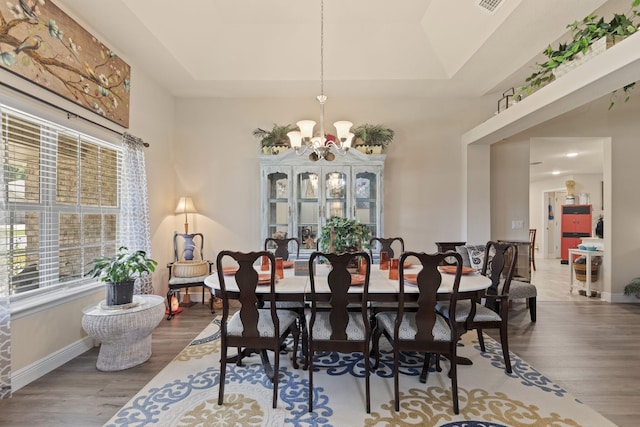 dining room with a tray ceiling, a chandelier, and wood-type flooring