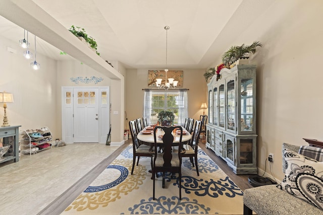 dining space with an inviting chandelier, wood-type flooring, and a tray ceiling