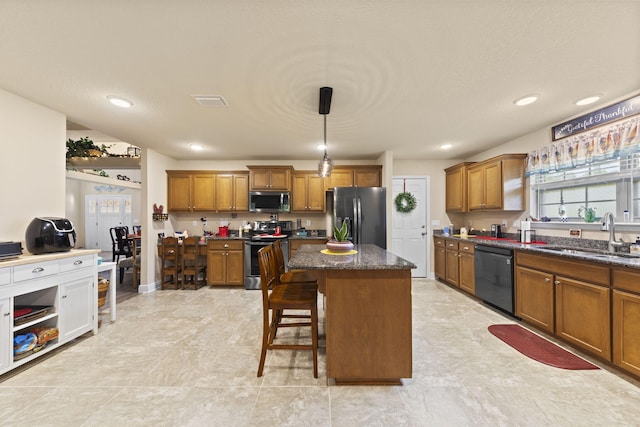 kitchen with stainless steel appliances, sink, light tile patterned floors, dark stone countertops, and hanging light fixtures