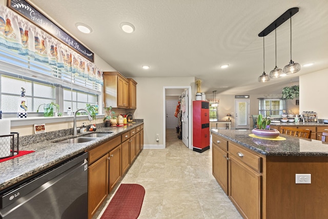 kitchen featuring dishwasher, sink, pendant lighting, light tile patterned flooring, and dark stone countertops