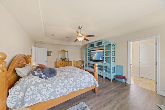 bedroom with a tray ceiling, ceiling fan, and wood-type flooring