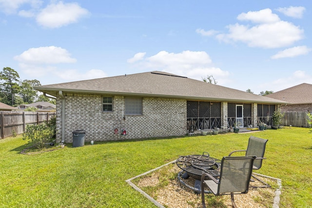 back of property with a yard and an outdoor fire pit