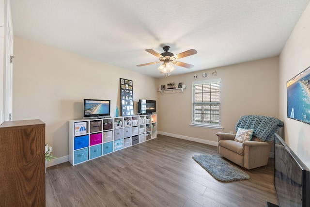 living area featuring ceiling fan and dark hardwood / wood-style flooring