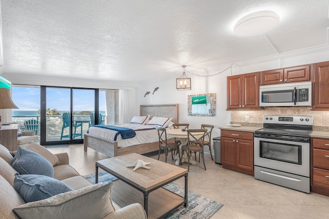 kitchen with light tile patterned flooring, appliances with stainless steel finishes, decorative backsplash, a water view, and a textured ceiling