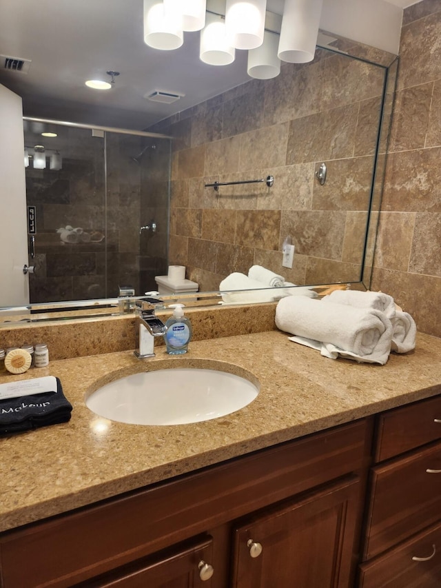 bathroom with tiled shower and vanity