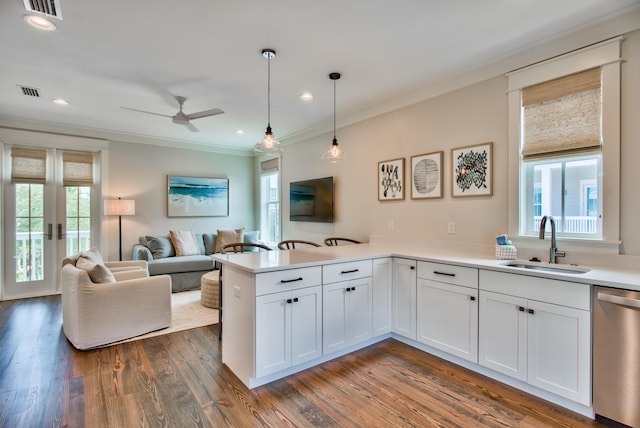 kitchen featuring white cabinets, stainless steel dishwasher, pendant lighting, sink, and kitchen peninsula