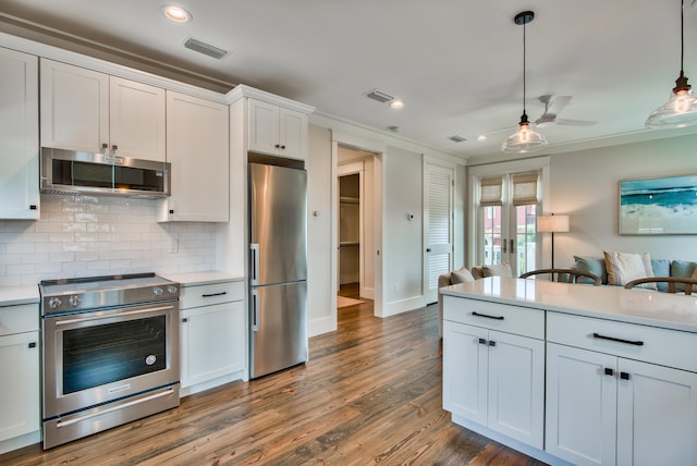 kitchen featuring white cabinetry, decorative light fixtures, tasteful backsplash, dark wood-type flooring, and appliances with stainless steel finishes