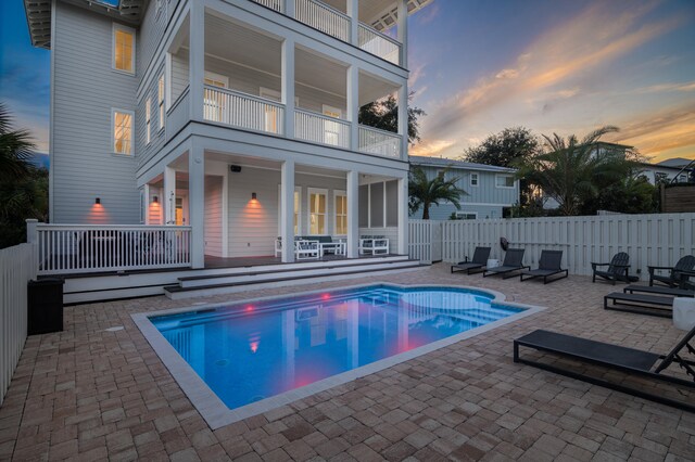 pool at dusk with a patio area