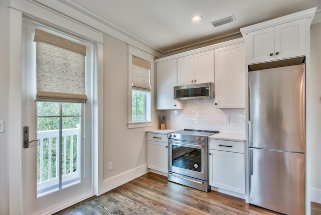 kitchen featuring white cabinets, appliances with stainless steel finishes, hardwood / wood-style flooring, and tasteful backsplash