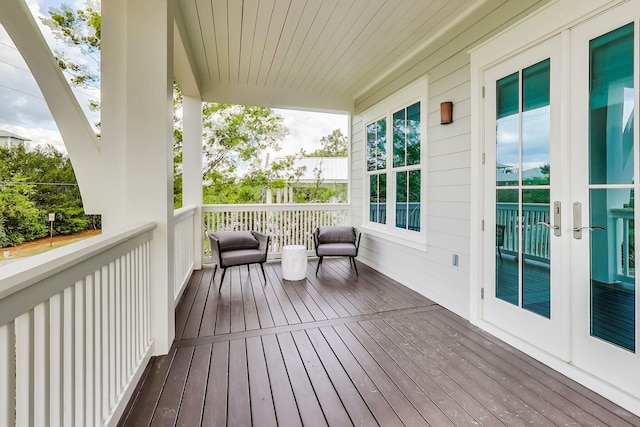 wooden terrace featuring covered porch and french doors