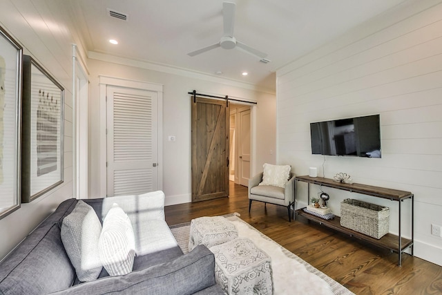 living room featuring ceiling fan, dark wood-type flooring, a barn door, and crown molding